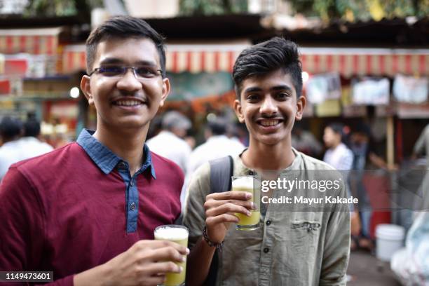 teenage boys drinking sugarcane juice on the street side - mumbai street stock pictures, royalty-free photos & images