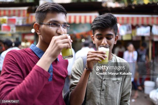 teenage boys drinking sugarcane juice on the street side - mumbai street stock pictures, royalty-free photos & images