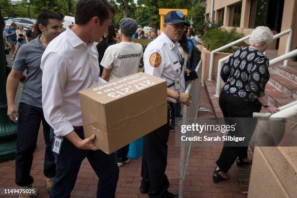 Representatives from the Democratic National Committee carry a box of signed petitions during a Greenpeace rally to call for a presidential campaign...