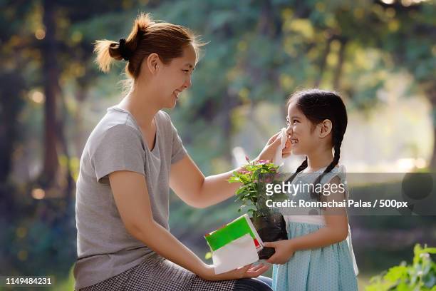 asian mother cleaning her daughter's face - chinese mothers day stockfoto's en -beelden