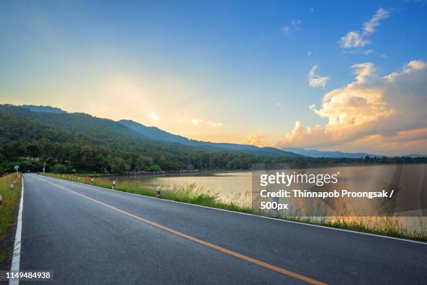 rural road with scenic view of the reservoir huay tueng tao with - rivier gras oever stockfoto's en -beelden