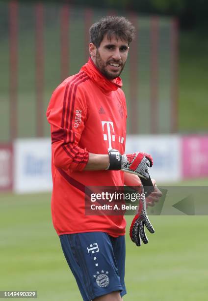 Javi Martinez of FC Bayern Muenchen smiles as he wears the goalkeeper glove of Manuel Neuer during their individual training session at the club's...