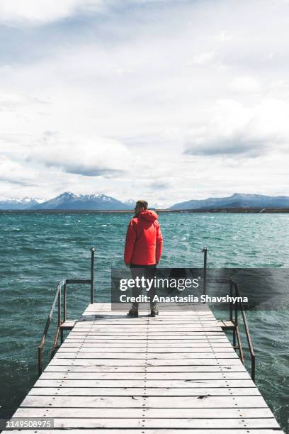 man stays on the pier looking at the ocean and mountains in puerto natales - puerto natales stock pictures, royalty-free photos & images