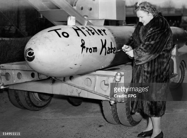American singer Kate Smith paints the message 'To Hitler from Kate' on the side of a torpedo at a US Navy submarine base in New London, Connecticut,...