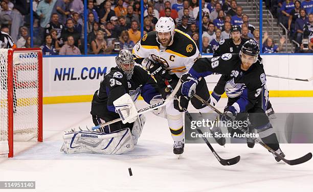 Zdeno Chara of the Boston Bruins tries to get the puck before Dwayne Roloson and Mike Lundin of the Tampa Bay Lightning during the second period in...