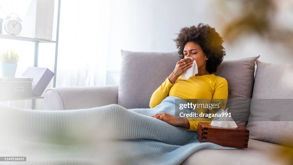 Woman sneezing in a tissue in the living room.