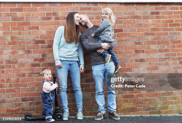 young family stood in front of red brick wall - series 4 3 stockfoto's en -beelden