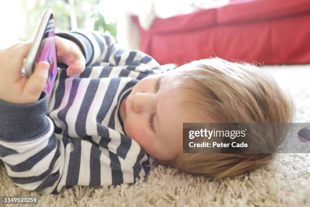 toddler laying down looking at phone - screen time stock pictures, royalty-free photos & images