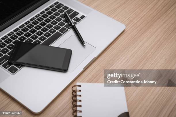 close up of laptop and cell phone on wooden desk - johnny stark stock pictures, royalty-free photos & images