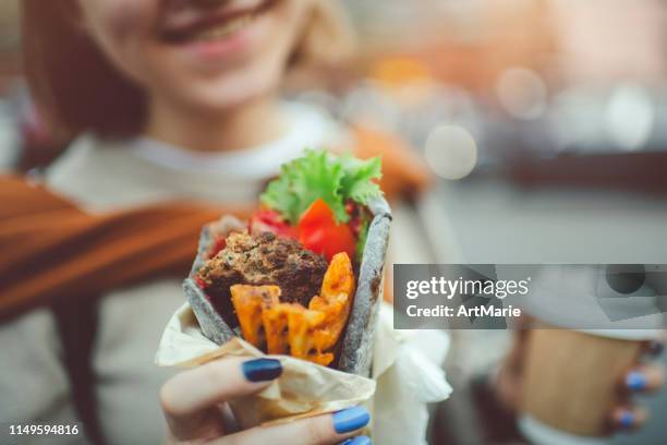 glückliches junges mädchen, das im sommer street food in der stadt genießt - shawarma stock-fotos und bilder