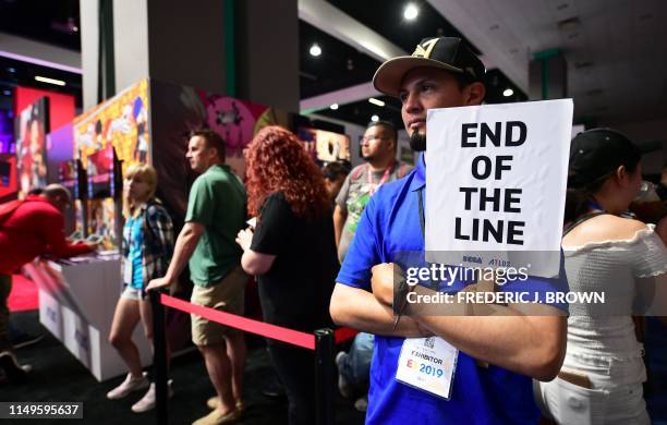 An "End of The Line" sign is held as people wait in long lines to preview games at the 2019 Electronic Entertainment Expo, also known as E3, on June...