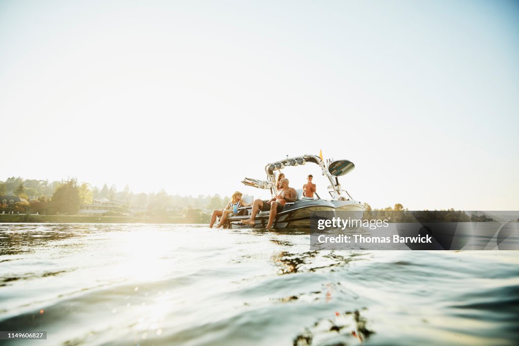 Smiling family relaxing on boat on lake on summer evening
