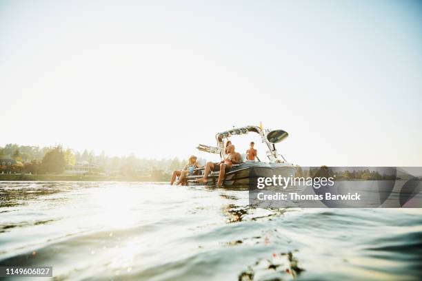 smiling family relaxing on boat on lake on summer evening - water craft stock pictures, royalty-free photos & images