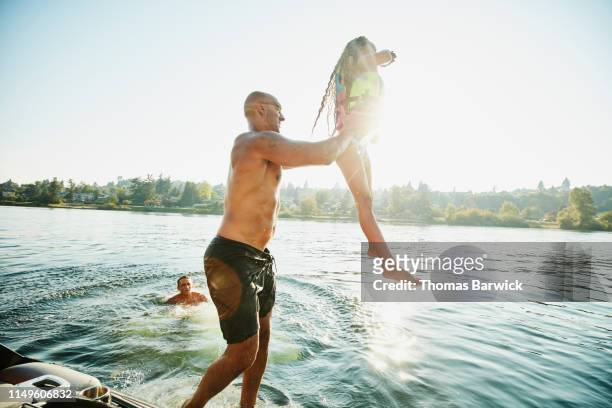 father throwing daughter into lake from boat on summer afternoon - summer super 8 stockfoto's en -beelden