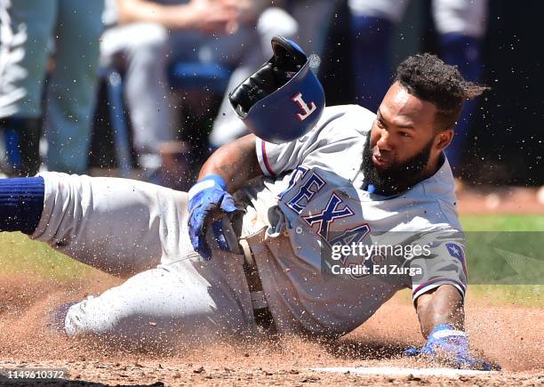 Danny Santana of the Texas Rangers slides into home to score on a Willie Calhoun two-run single in the fifth inning at Kauffman Stadium on May 16,...