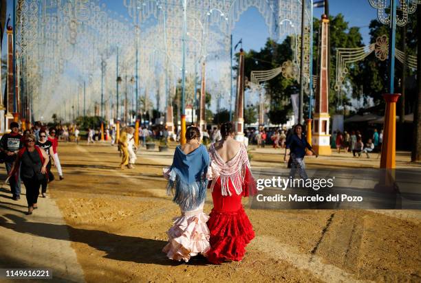 Women wearing traditional flamenco dresses walk during the 'Feria del Caballo' on May 16, 2019 in Jerez de la Frontera, Spain. The Jerez Horse Fair,...