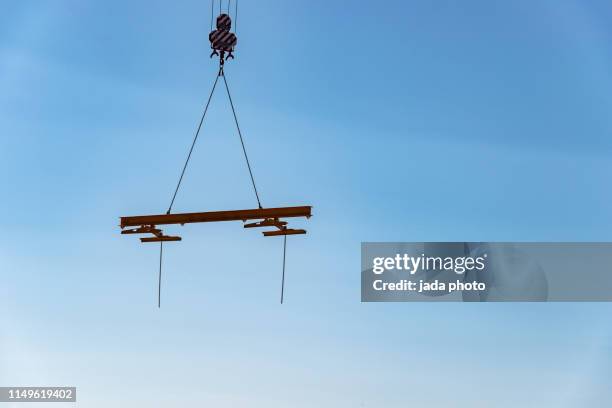 steel beam hangs high in the air - crane stock pictures, royalty-free photos & images