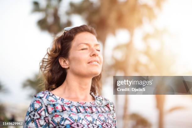 feliz día de la mujer madura soñando con los ojos cerrados mientras que en unas vacaciones. - woman day dreaming fotografías e imágenes de stock