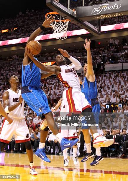 Dwyane Wade of the Miami Heat goes up for a shot between Brendan Haywood and Peja Stojakovic of the Dallas Mavericks in the first half in Game One of...