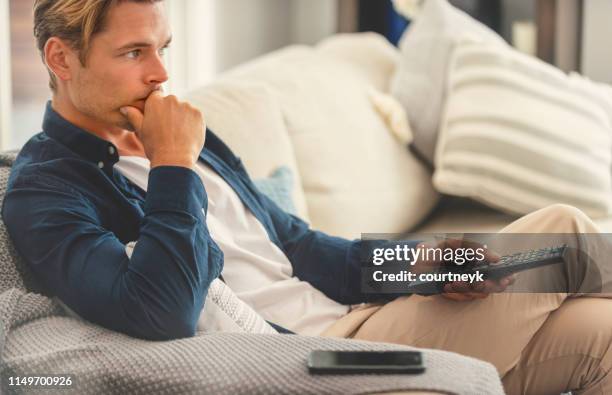 uomo seduto sul divano a guardare la televisione. - man watching tv foto e immagini stock