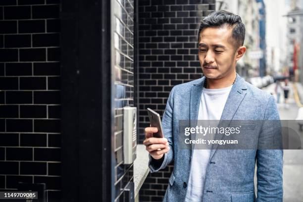 homem chinês que entra em sua home com seu smartphone - ringing doorbell - fotografias e filmes do acervo