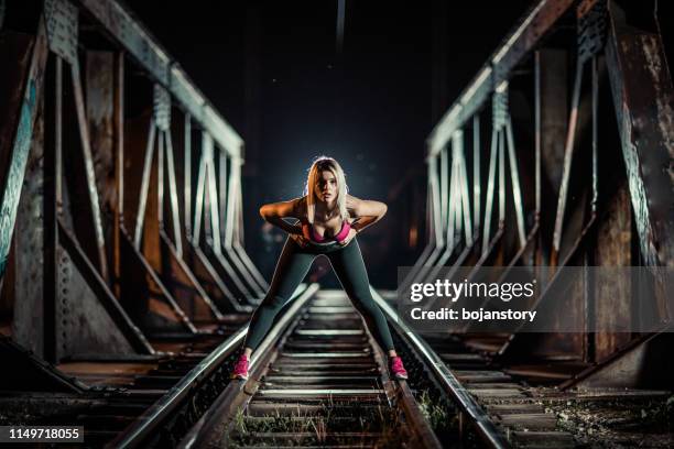 junge frau trainiert nachts auf der bahn - railway bridge stock-fotos und bilder