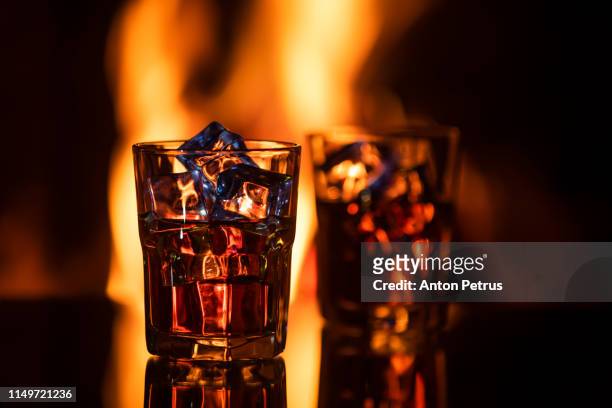 glass of whiskey with ice near the fireplace - cognac brandy stock pictures, royalty-free photos & images