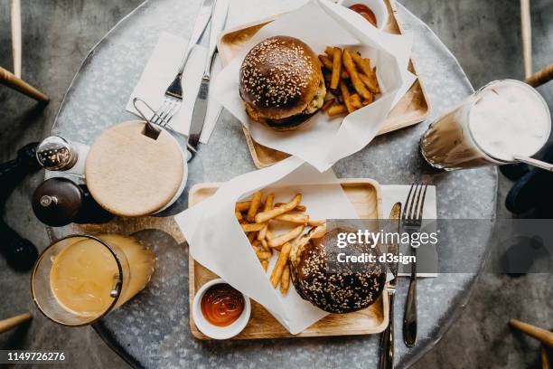 top view of burgers with french fries and drinks freshly served on table in cafe - burger overhead stock-fotos und bilder