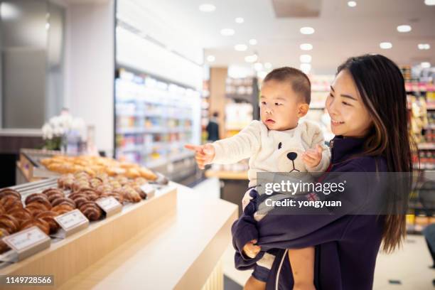 matriz asiática que carreg seu filho em um supermercado - baby pointing - fotografias e filmes do acervo