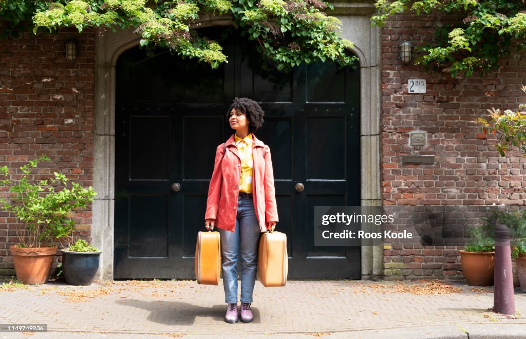 A young woman holding suitcases.
