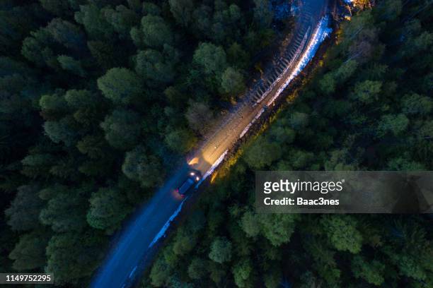 car with light on driving on a country road in the evening, norway - car country road photos et images de collection