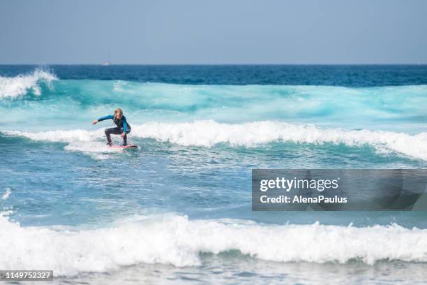 woman surfing on waves in tenerife, playa de las americas, spain - playa de las americas stock pictures, royalty-free photos & images