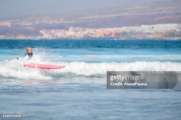 woman beginner surfer on waves in tenerife, playa de las americas, spain - playa de las americas stock pictures, royalty-free photos & images