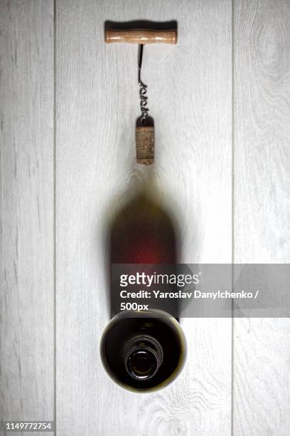 bottle of red wine with cork on white wooden table - wine cork stockfoto's en -beelden