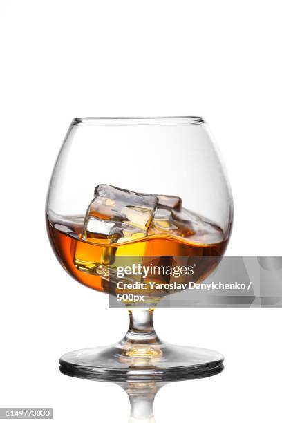 splash of whiskey with ice in glass isolated on white background - cognac brandy stock pictures, royalty-free photos & images