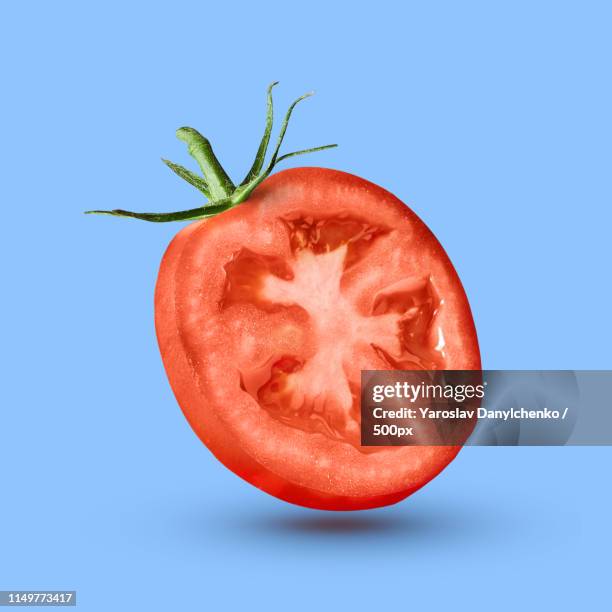 half tomato over a blue background - tomates photos et images de collection