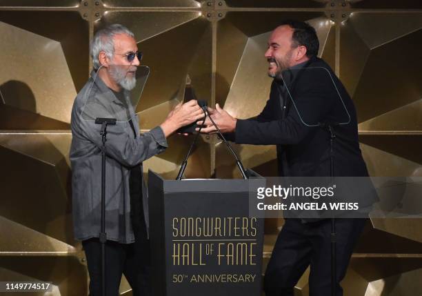 English singer-songwriter Yusuf Islam accepts his award from US musician Dave Matthews as he is inducted into the Songwriters Hall of Fame onstage...