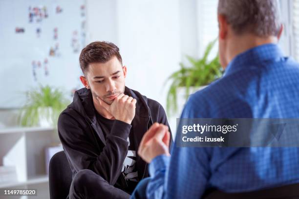 male student listening to therapist in session - university student support stock pictures, royalty-free photos & images