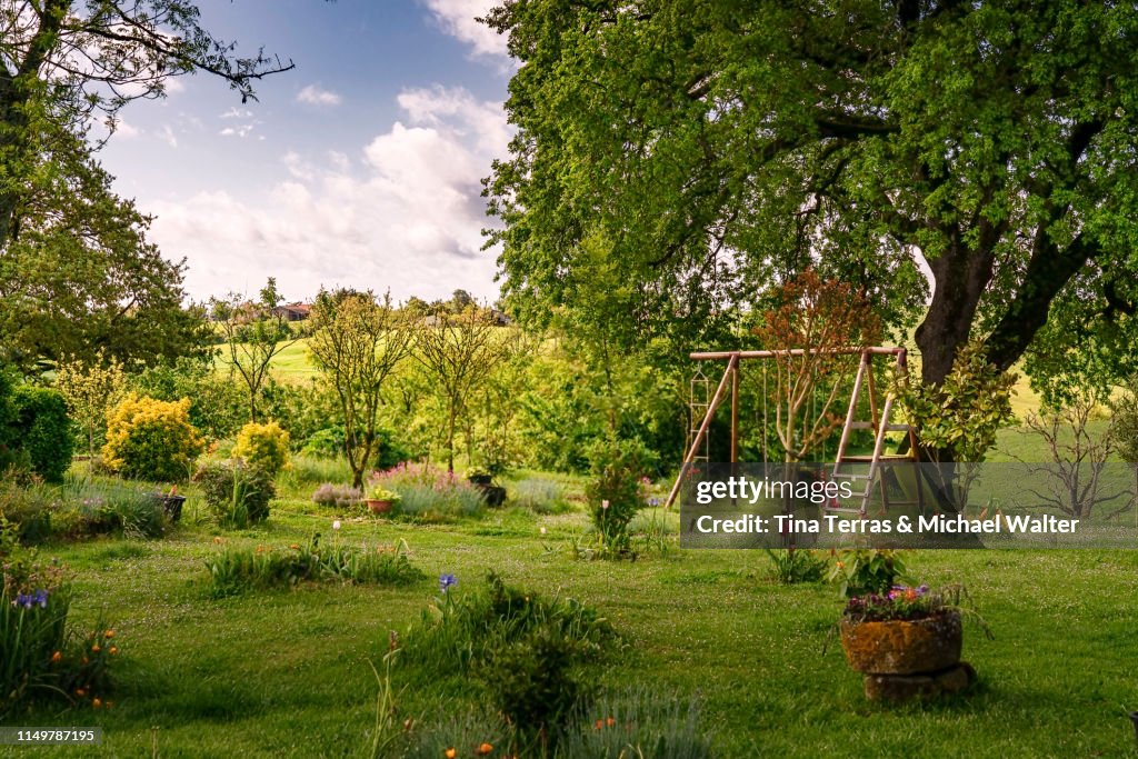 Beautiful garden with flowers, lawn and children's toys in France.