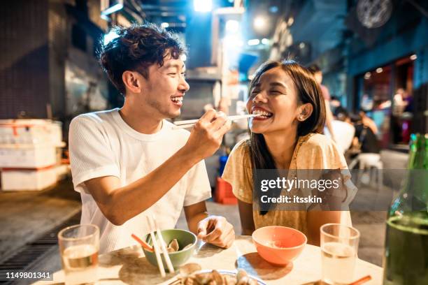 asian couple enjoying street food in hong kong - chinese noodles stock pictures, royalty-free photos & images