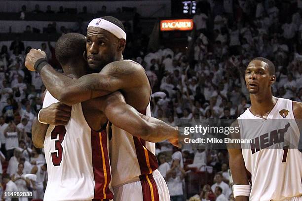 LeBron James and Dwyane Wade of the Miami Heat hug alongside teammate Chris Bosh of the Miami Heat after the Heat defeat the Dallas Mavericks 92-84...