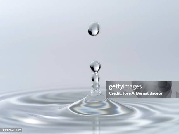 group of drops on line suspended in the air, falling down on a water surface that forms figures and abstract forms, on a white background. - tropfen aufprall stock-fotos und bilder