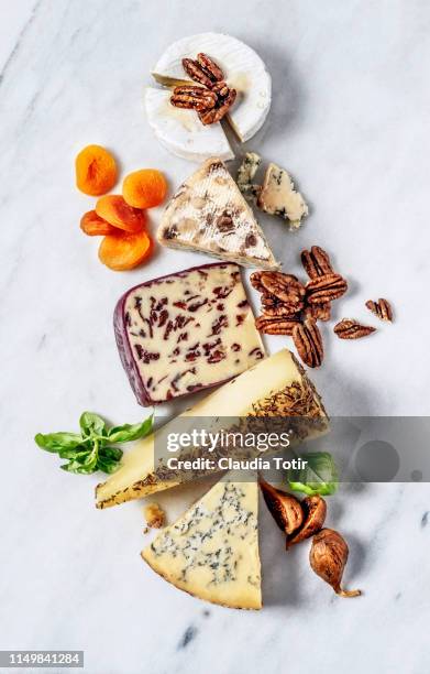 french cheese served with dried fruit, and walnuts on a marble cutting board - cheese board photos et images de collection