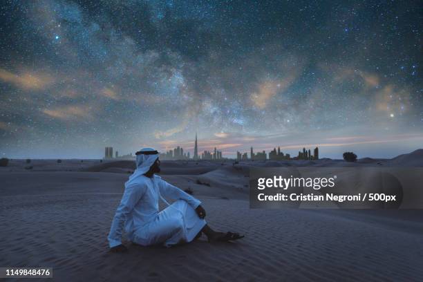 arabic man with kandura walking in the desert at sunset time - arabian desert adventure night photos et images de collection