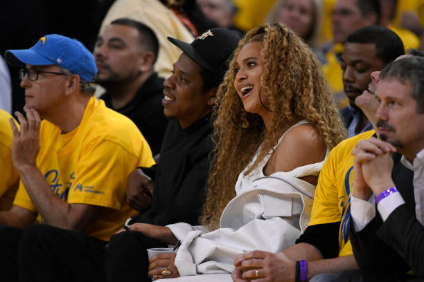 Jay-Z y Beyonce reaccionan mientras están sentados al lado de la cancha durante el segundo cuarto del Juego 1 de las semifinales de la Conferencia Oeste de la NBA en el Oracle Arena en...