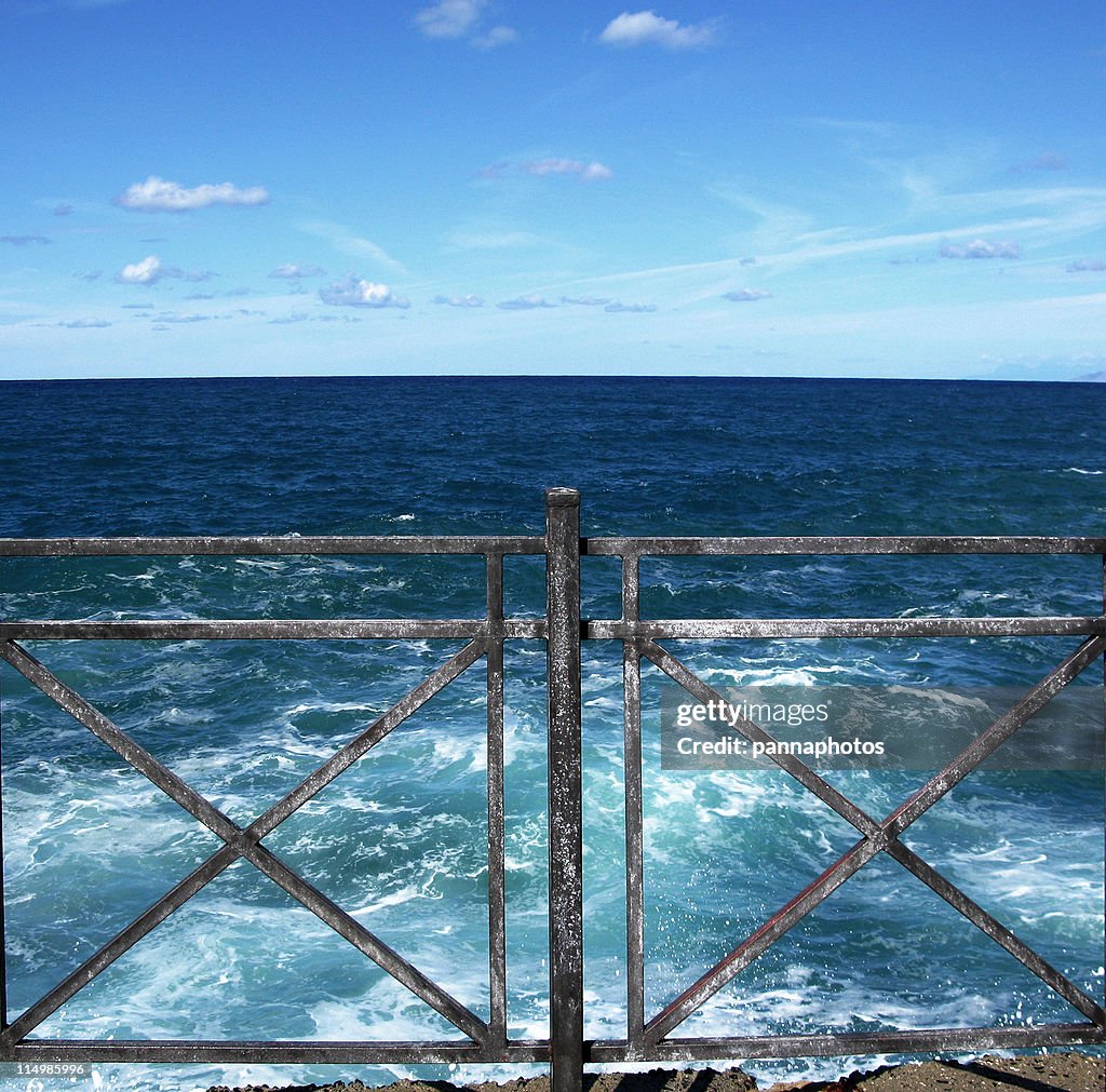 Banister in front of turbulent sea