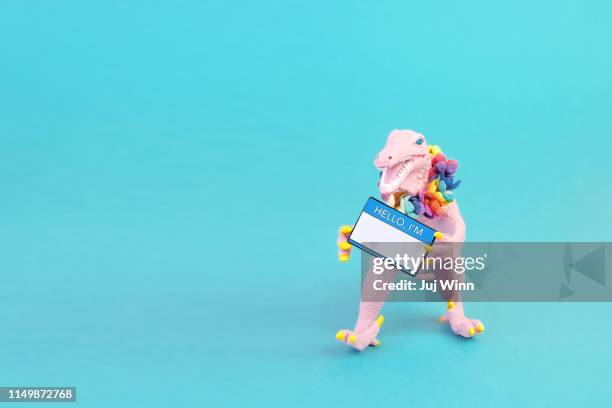 toy dinosaur with "hello i'm" name tag - funny dinosaur stock pictures, royalty-free photos & images