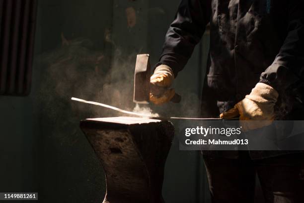 schmied schmiedet eine eisenstange auf amboss-block - sledgehammer stock-fotos und bilder