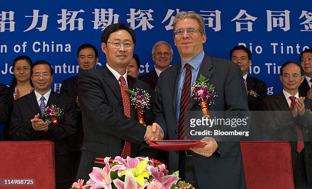 Xiong Weiping, chairman of Aluminum Corp.of China , center left, and Tom Albanese, chief executive officer of Rio Tinto Plc, center right, shake...