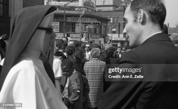 View, between an unidentified nun and a clergy member, of marchers as they gather on a downtown street for the 'Walk for Understanding' through the...